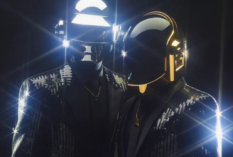 Daft Punk en vestes à paillettes avec leurs casques argenté et doré éclairés en contre-jour