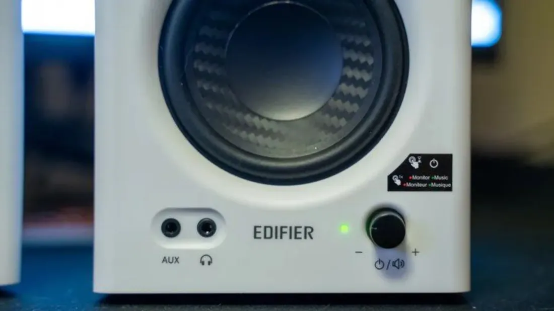 Détail de la façade de l'enceinte active Edifier MR4 blanche : prises AUX et casque, logo Edifier, LED de mode verte et molette multifonction