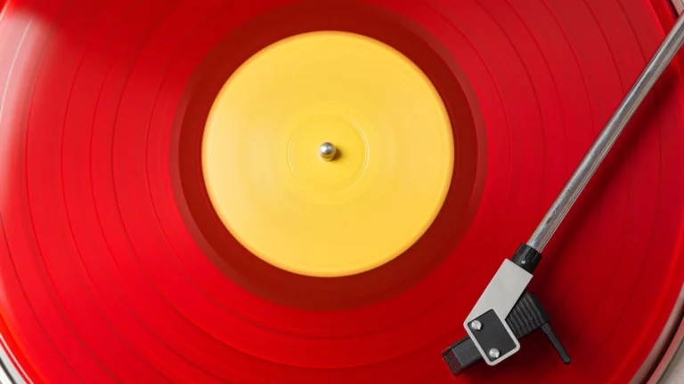 Vinyle couleur rouge translucide en cours de lecture sur une platine, bras et cellule posés sur le disque